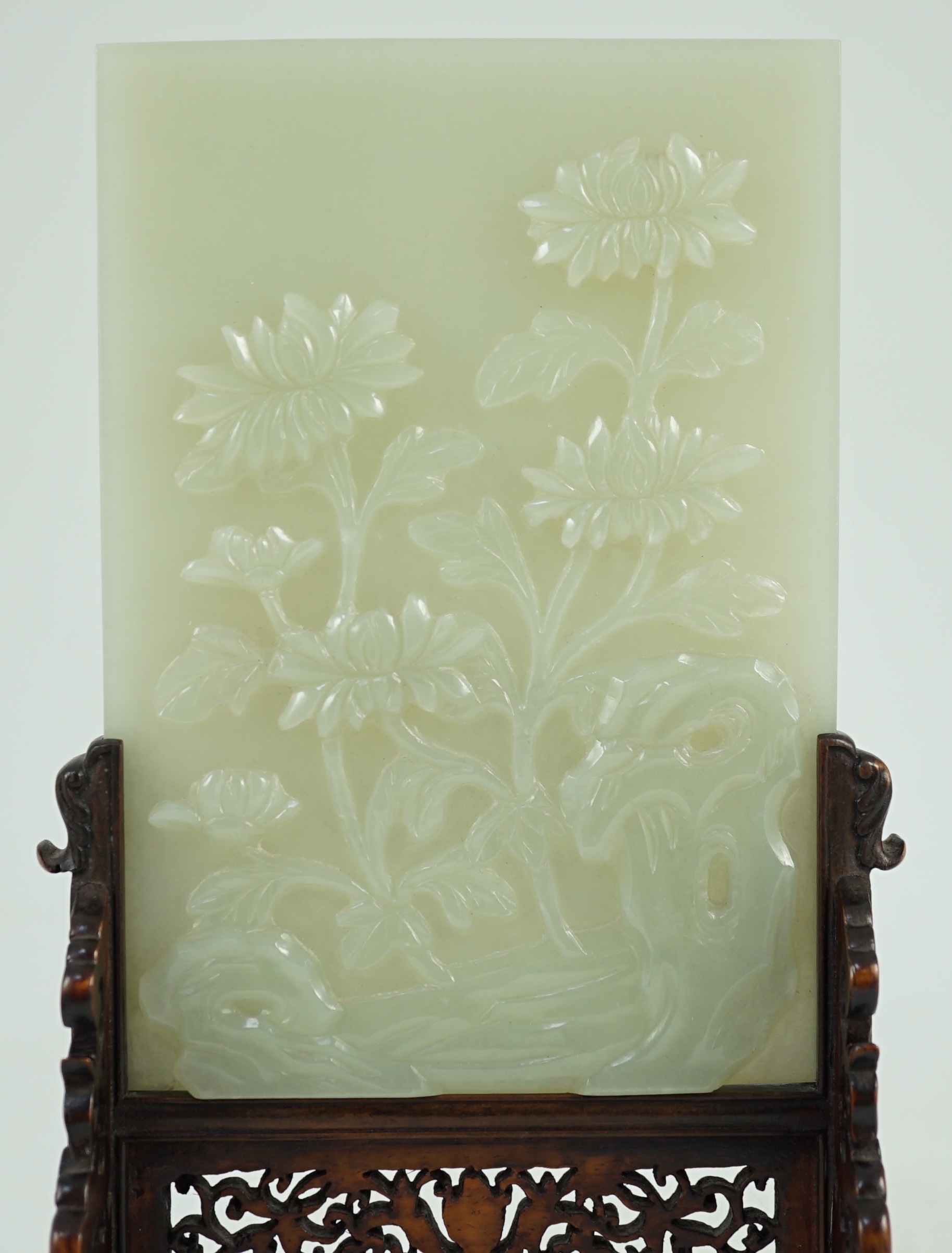 A good Chinese celadon jade ‘peonies and rockwork’ small table screen and stand, 18th/19th century, Jade 14.7 cm x 10.3cm, total size including carved wood stand 22cm x 12.3cm